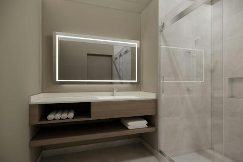 a bathroom with a sink and a mirror and a shower at Courtyard by Marriott Quito Airport in Quito