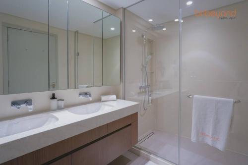 a bathroom with a sink and a shower with a mirror at Exclusive Home with Private Beach in Dubai