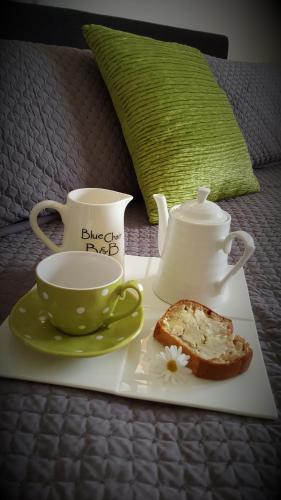 a tray with a cup and a tea pot and a plate of bread at Kerikeri Blue Chair B&B in Kerikeri