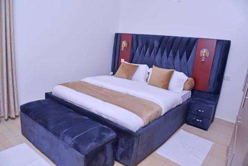 a large bed with a blue headboard and pillows at Betty's Apartments in Ntabwe