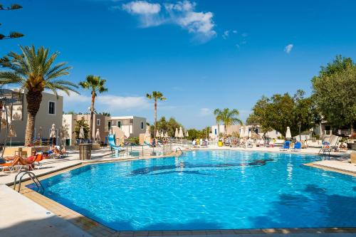 a large blue swimming pool with people sitting around it at Sirios Village Hotel & Bungalows - All Inclusive in Kato Daratso