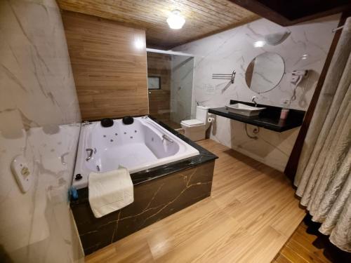 a bathroom with a tub and a toilet and a sink at Pousada Kaetê in Paraty