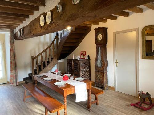 a dining room with a table and a grandfather clock at Séjour à la campagne in Crévin