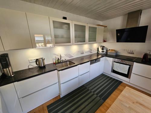 una cucina con mobili bianchi e un lavandino di Charmantes Landhaus mit Garten - Nähe Alpen und Seen a Penzberg