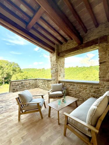 a patio with a couch and chairs and a table at Torre della Soara - Medieval Tower in the Umbrian Countryside in Città di Castello