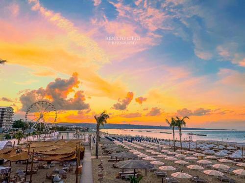 a beach with umbrellas and a ferris wheel at sunset at Bellavista in San Salvo
