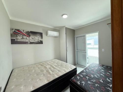 une petite chambre avec deux lits et une fenêtre dans l'établissement Apartamento Vista Mar Mirim 2 Dormitorios suite com Wifi para até 8 pessoas 1 vaga de estacionamento, à Praia Grande