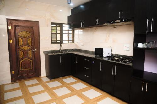 a kitchen with black cabinets and a brown door at Cremyark Homes in Benin City