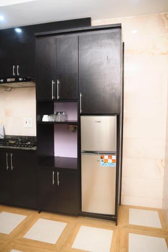 a refrigerator in a kitchen with black cabinets at Cremyark Homes in Benin City