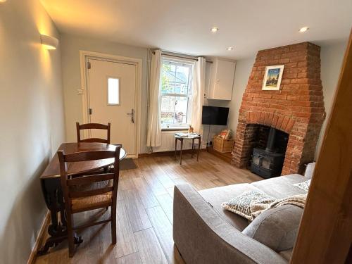 a living room with a couch and a brick fireplace at Cottage, Central Saffron Walden, Garden, Little Braybrooke in Saffron Walden