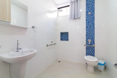 a white bathroom with a sink and a toilet at Aldeia Da Lagoinha in Ubatuba