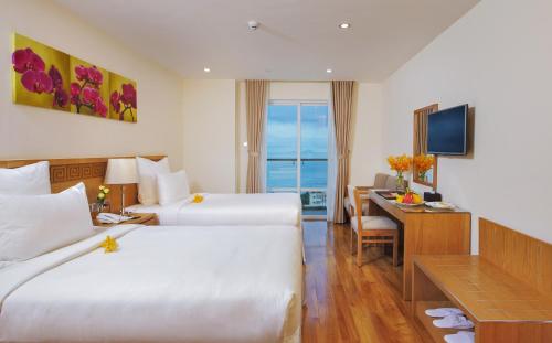 a hotel room with two beds and a desk at Rosaka Nha Trang Hotel in Nha Trang