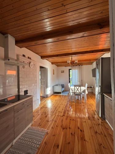 a kitchen with wooden ceilings and a table and chairs at Domek nad rzeką in Zatory
