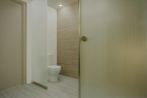 a bathroom with a toilet and a glass door at AC Hotel by Marriott Georgetown Guyana in Georgetown