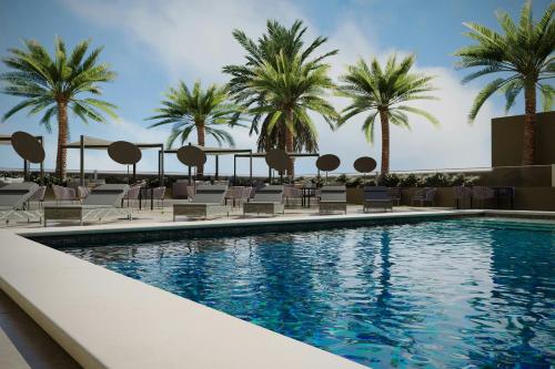 a swimming pool with chairs and palm trees at AC Hotel by Marriott Georgetown Guyana in Georgetown
