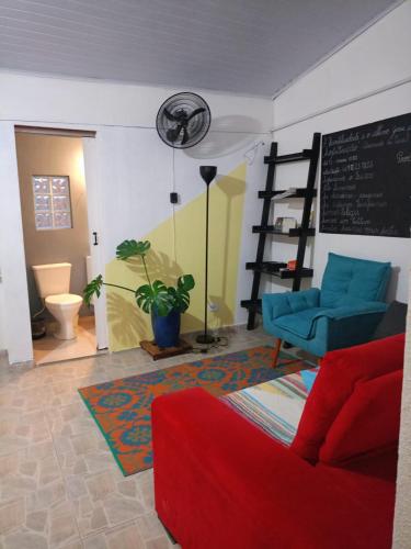 a living room with a red couch and a chalkboard at Varanda Hospedaria - SP Expo Hospedagem in Sao Paulo