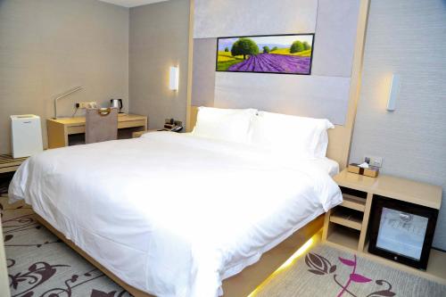 a bedroom with a large white bed and a desk at Lavande Hotel Baiyun International Airport Branch in Guangzhou