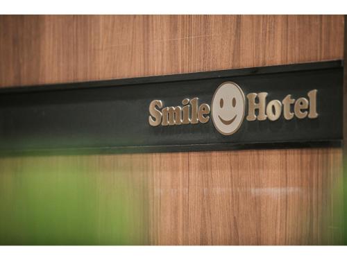 a sign for a smile hotel on a wooden door at Smile Hotel Hakata Ekimae - Vacation STAY 64014v in Fukuoka