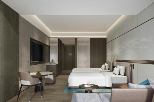 a hotel room with a large bed and a table at Courtyard by Marriott Zhuhai in Zhuhai