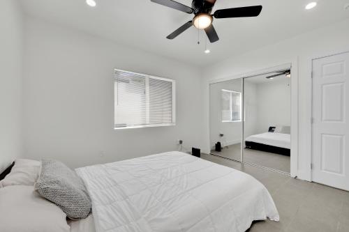 Habitación blanca con ventilador de techo y espejo. en Mid-City Retreat With Backyard And Grill, en Los Ángeles