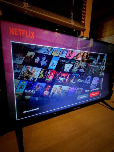 a flat screen tv sitting on top of a table at Chalet cosy & jacuzzi privé - Paris & Disney in Ormesson-sur-Marne