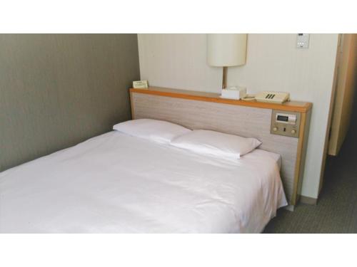 a bed in a hotel room with a phone next to it at Smile Hotel Shimonoseki - Vacation STAY 12519v in Shimonoseki