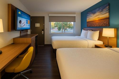 a hotel room with two beds and a desk and a tv at Days Inn by Wyndham Rock Springs in Rock Springs
