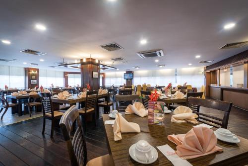 comedor con mesas y sillas de madera en Hotel Sentral Riverview Melaka, en Melaka