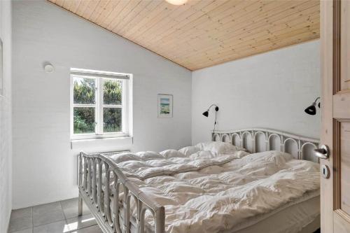 a bed in a white bedroom with a window at 10704-Ulfborg-Gaffelbjergvej-49 in Øhuse