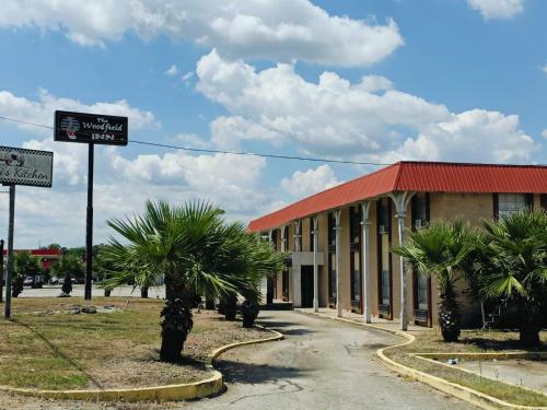 YoakumにあるWoodfield Inn & Suites Hotel O, Yoakum TX 111の赤い屋根と正面にヤシの木がある建物