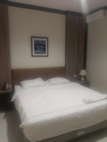 a large bed with white sheets and pillows at Kayana Homestay Palu 