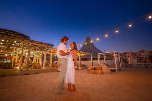 a bride and groom standing on the beach at night at Sandos Finisterra All Inclusive in Cabo San Lucas