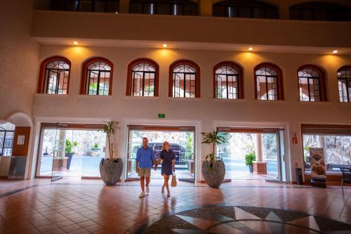 a man and a woman walking into a building at Sandos Finisterra All Inclusive in Cabo San Lucas