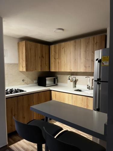a kitchen with wooden cabinets and a table with chairs at Apartamento en Ríonegro con excelente ubicación in Rionegro