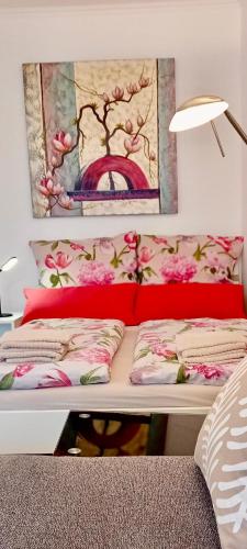 a bed with red pillows and a painting on the wall at Studio apartment with balcony in Ingolstadt