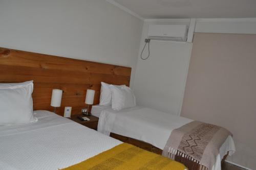 a hotel room with two beds and a window at De Triana Hotel in Rancagua