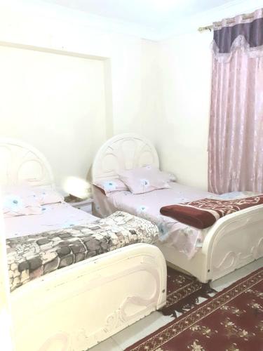 ミニヤーにあるFurnished apartment in Minya with archaeological toursのカーテン付きの客室で、ツインベッド2台が備わります。