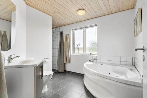 een witte badkamer met een bad en een toilet bij 60836-Ulfborg-Fjand-Strand-29 in Fjand Gårde