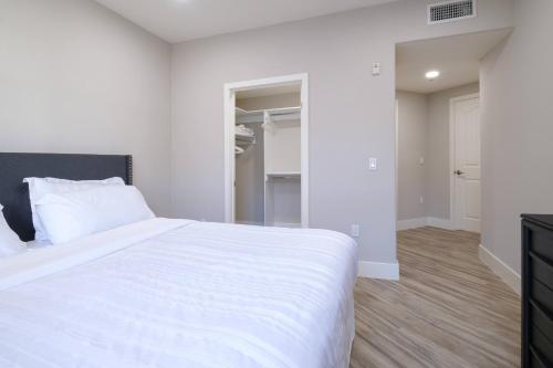 a bedroom with a white bed and a walk in closet at Multiple Miracle Mile Apartments Hub in Los Angeles