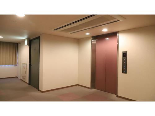an empty hallway with a red door in a building at Smile Hotel Takaoka Ekimae - Vacation STAY 89663v in Takaoka