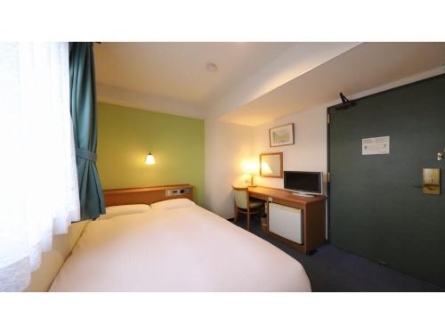 a bedroom with a bed and a desk with a computer at Smile Hotel Takaoka Ekimae - Vacation STAY 89632v in Takaoka