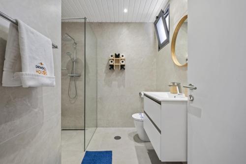 a bathroom with a toilet and a glass shower at Orinoco Sunset House II - Private Pool & Garden in Calheta