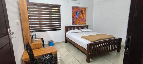a bedroom with a bed and a table and a window at Sea Breeze Cherai Homestay in Pallipuram