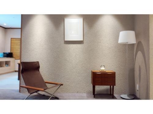 a room with a chair and a table and a lamp at DIG the Osaka - Vacation STAY 14513v in Suita