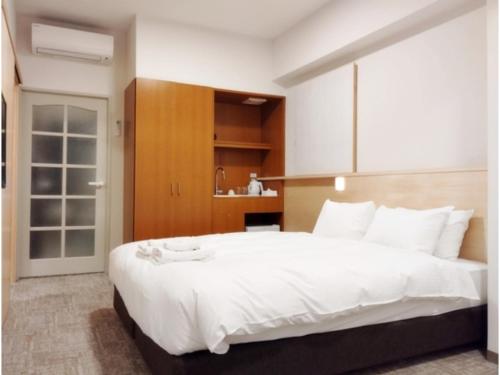 a bedroom with a large white bed and a kitchen at DIG the Osaka - Vacation STAY 14520v in Suita