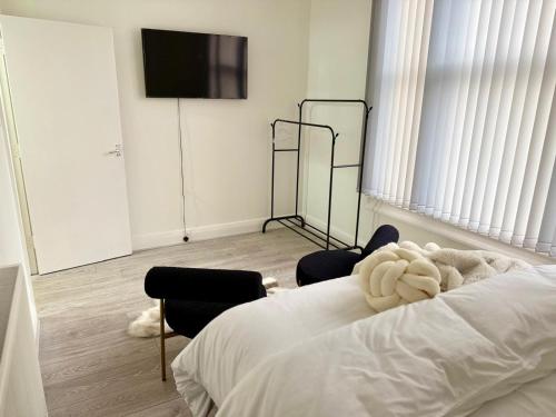 a bedroom with a bed and two chairs and a flat screen tv at Edgbaston Retreat-Birmingham City Centre-Double Room in a shared two bedroom apartment in Birmingham