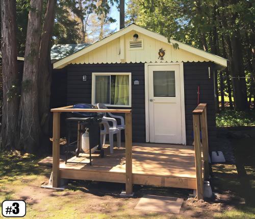 Un pequeño cobertizo negro con una mesa y una mesa. en Ambleside - 1-Bedroom Cottage #3, en Kawartha Lakes