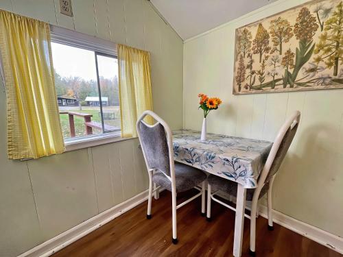 a dining room table with chairs and a vase of flowers on it at Ambleside - 1-Bedroom Cottage #3 in Kawartha Lakes