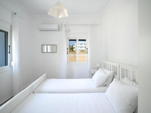 two beds in a white room with a window at Casa Kamara in Kardamaina