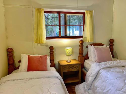 Ambleside - 2-Bedroom Cottage #4 في كاوارثا ليك: غرفة نوم بها سريرين ونافذة